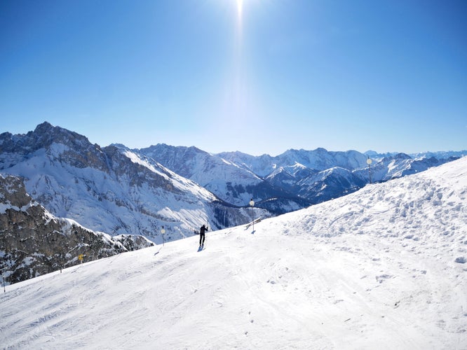 Photo of snowboarder on the slopes high in the Alps between Germany and Austria with snow, blue sky and sunlight.