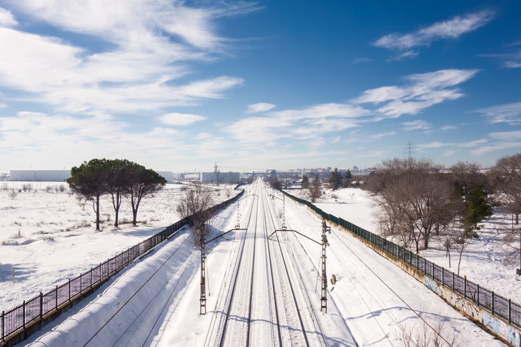 Snowy train tracks in Coslada on a cold winter's day, on a blue sky morning with some clouds.