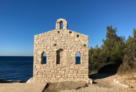 Photo of stone temple  wall, by the sea on top of the rocky coast near Verudela Canyon, Pula, Croatia.