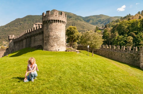 photo of woman sitting on the green lawn of Montebello Castle in Bellinzona town, Ticino, Switzerland.