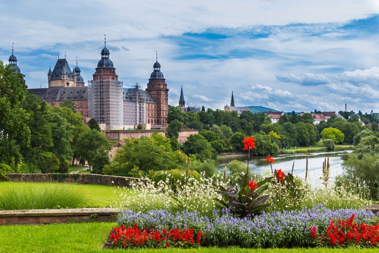 photo off view of Beautiful view of the old town Aschaffenburg, Germany and the palace Johannisburg on shore of river Main on the background of blue cloudy sky and green plants and flowers. Tourist attraction.