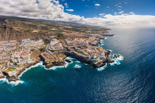 photo of aerial shot of Costa Adeje area, South Tenerife, Spain. Captured at golden hour, warm and vivid sunset colors. Luxury hotels, villas and restaurants behind the beach.