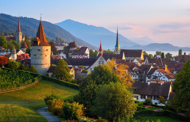 Photo of View of Zug city's medieval Old town and surrounding swiss Alps mountains in sunset light, Switzerland.