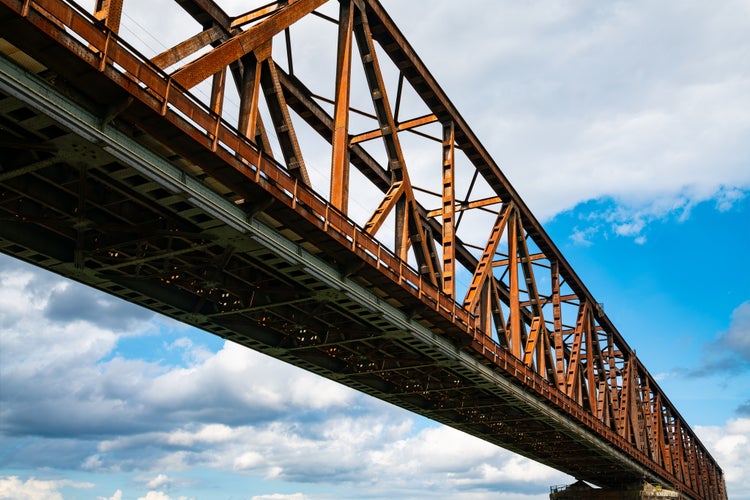 Photo of Photo of Historic railway bridge over river Rhine in Duisburg, Germany. Steel rivet construction with diagonal truss beams is in bad condition with rusty surface. Main railroad from Ruhr basin to Aachen.