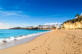 Photo of beautiful aerial view of the sandy beach surrounded by typical white houses in a sunny spring day, Carvoeiro, Lagoa, Algarve, Portugal.