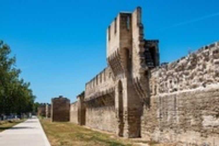 View of the walls and towers around the city center of Avignon, under a sunny blue sky. France