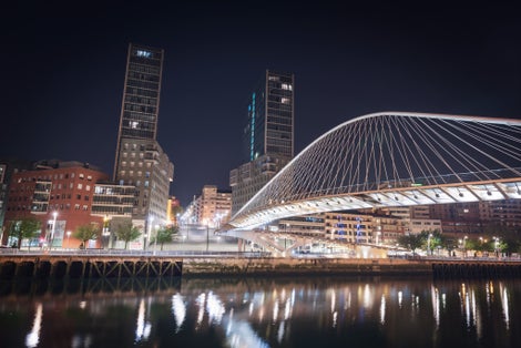 Photo of Bilbao cityscape and pedestrian zubizuri bridge at night, Bilbao, Basque country, Spain.