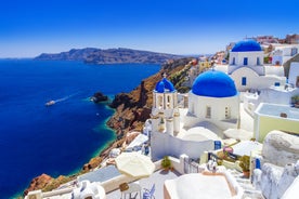 Photo of aerial view of black Perissa beach with beautiful turquoise water, sea waves and straw umbrellas, Greece.