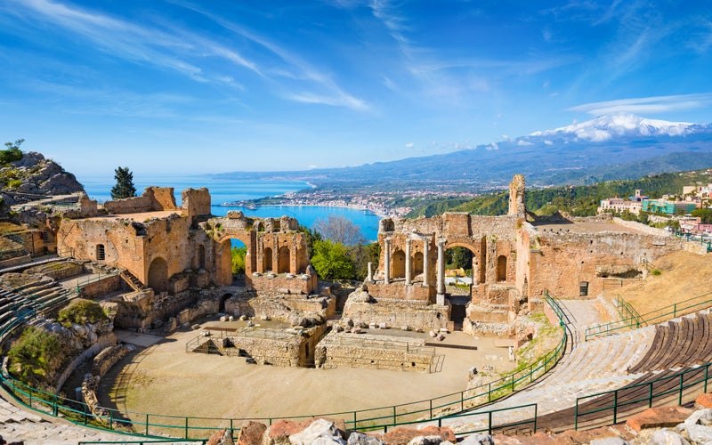 Photo of ruins of Ancient Greek theatre in Taormina located in Metropolitan City of Messina on background of Etna Volcano, Italy.