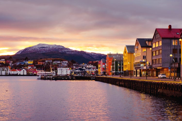 photo of view of Kristiansund, Norway. View of city center of Kristiansund, Norway during the cloudy morning at sunrise with colorful sky. Port with historical buildings.