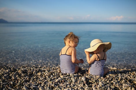 Photo of the baby playing with her sister on the beach in Kemer, Turkey. Concept vacation with children.