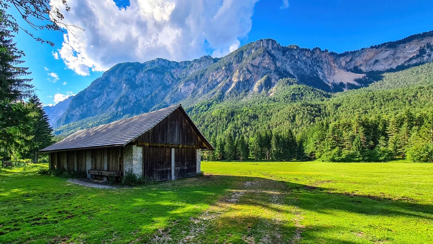 An abandoned hut with a scenic view on mount Dobratsch in the natural park Dobratsch in Villach, Carinthia, Austria. Gailtaler and Villacher Alps. Lush green alpine meadow. Breathing. Remote Location