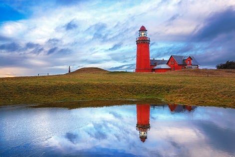 Photo of beautiful red Lighthouse Bovbjerg Fyr with green grass and blue sky, Danish North Sea coast, Jutland, Denmark.