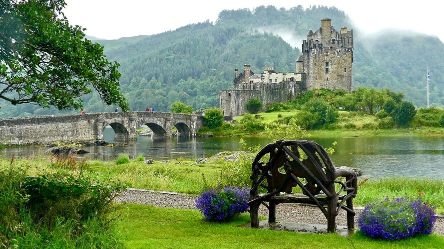 Visitors walk along the stone bridge leading to Eilean Donan Castle.jpg