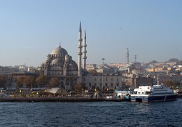 Touristic sightseeing ships in Golden Horn bay of Istanbul and mosque with Sultanahmet district against blue sky and clouds. Istanbul, Turkey during sunny summer day.