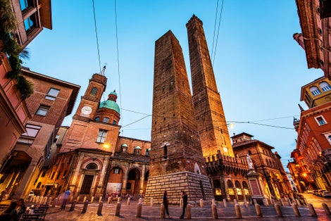 photo of Two famous falling Bologna towers Asinelli and Garisenda. Evening view, long exposure. Bologna, Emilia-Romagna, Italy.