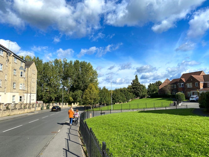 Looking along, Whitechapel Road, with housing and green spaces, on a sunny day in, Cleckheaton, Bradford, UK