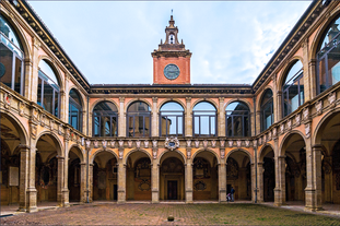 Photo of Italy Piazza Maggiore in Bologna old town tower of town hall with big clock and blue sky on background, antique buildings terracotta galleries.