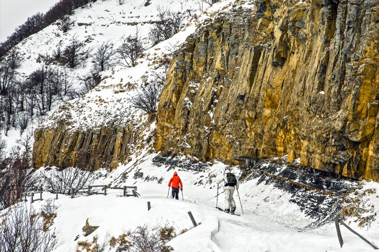 Schia, Parma, Italy - Two man practicing alpine ski near a vertical snow capped rock mountain