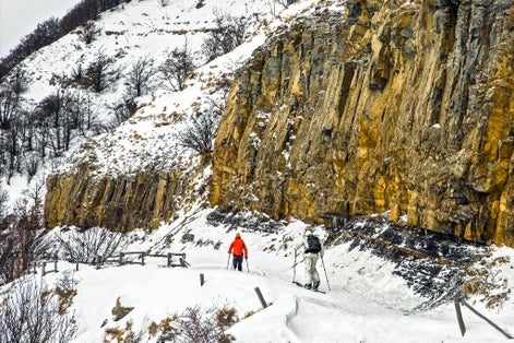 Schia, Parma, Italy - Two man practicing alpine ski near a vertical snow capped rock mountain