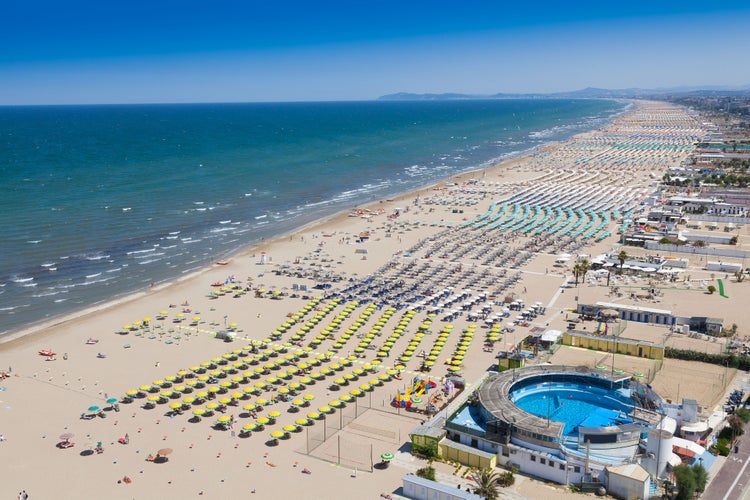 Photo of aerial view of umbrellas and chaise lounges on the beautiful beach of Rimini in Italy.