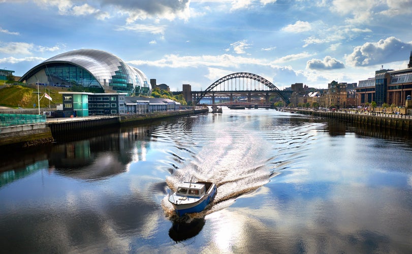 photo of view of A boat sailing down the River Tyne with Newcastle Tyne Bridge in the distance.