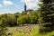 View of Kelvingrove Park full of people enjoying the Scottish summer with the main building of Glasgow University on the top of the hill.