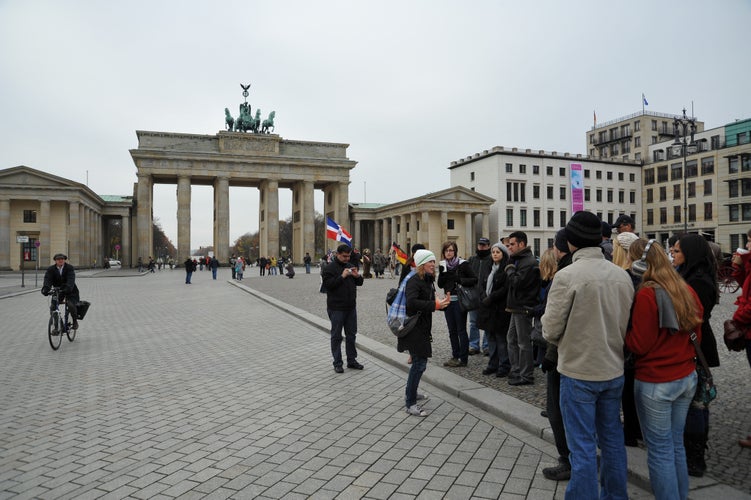 A tour guide speaks to tour group walking in front of the famous Brandenburg Gate on Pariser Platz.jpg