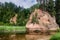 Summer landscape of red stone cliff of Zvartes rock Zvārtes iezis in the basin of Amata river, Latvia.