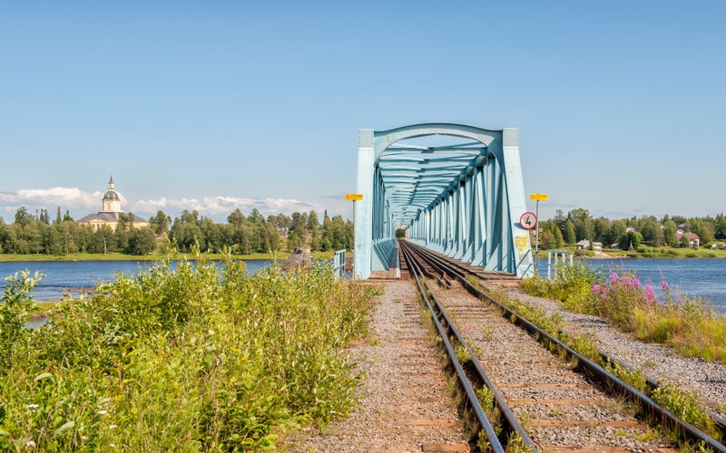 Photo of Torne river railway bridge at the border between Sweden and Finland and the historic church of Tornio in Finnish Lapland.