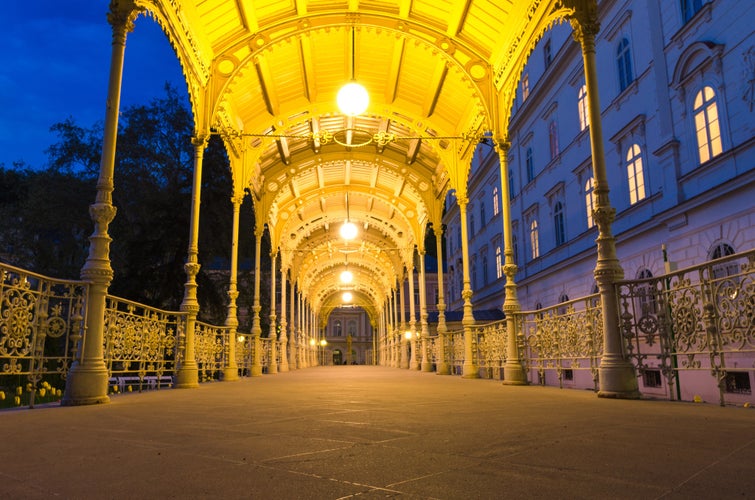 Photo of park Colonnade with wooden arbor and lights in Dvorak Park Dvorakovy sady in Karlovy Vary (Carlsbad) historical city centre, evening twilight view, West Bohemia, Czech Republic.