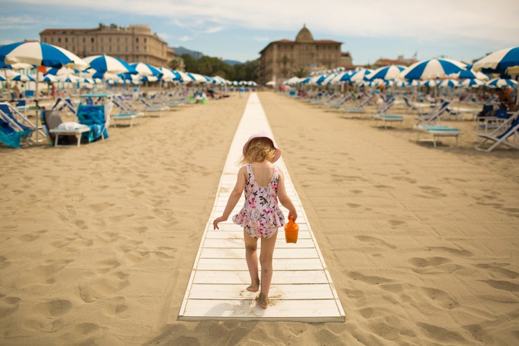 A little girl walks on the sand on the beach of Viareggio (Italy). 