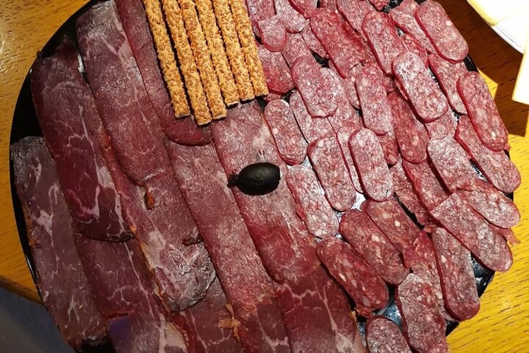 A platter showcasing cured meats, including salami and beef cuts, neatly arranged with breadsticks and a single black olive as garnish..jpg