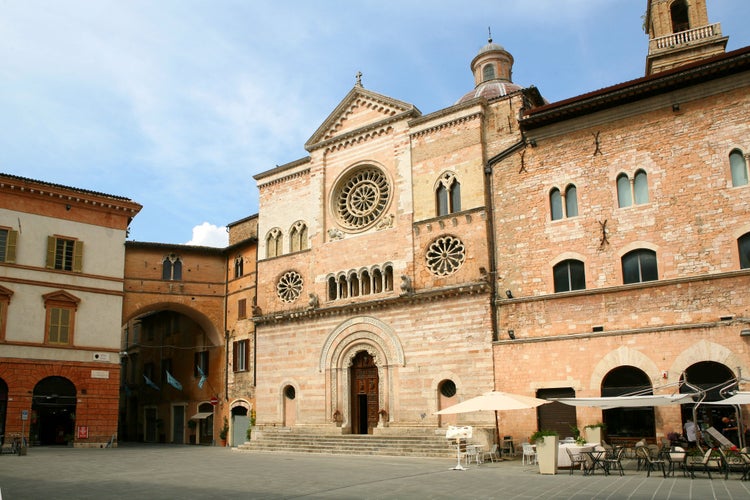 Photo of the Cathedral of San Feliciano in the square of Foligno. The side facade, with 3 rosettes, mullioned windows, arches and columns, Italy.