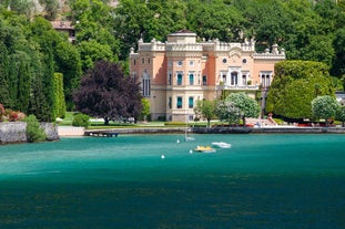 Photo of Old harbour Porto Vecchio with motor boats on turquoise water, green trees and traditional buildings in historical centre of Desenzano del Garda town, Northern Italy.