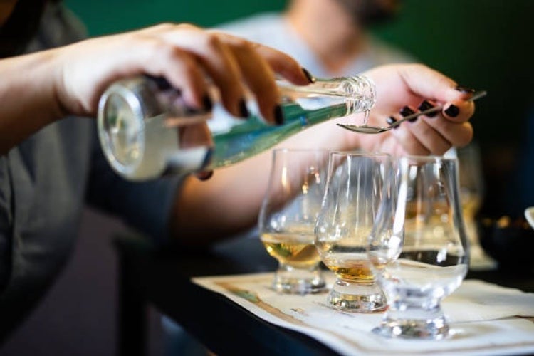 A person carefully pouring water into a Glencairn glass of single malt whisky, enhancing the flavors of the whisky.jpg