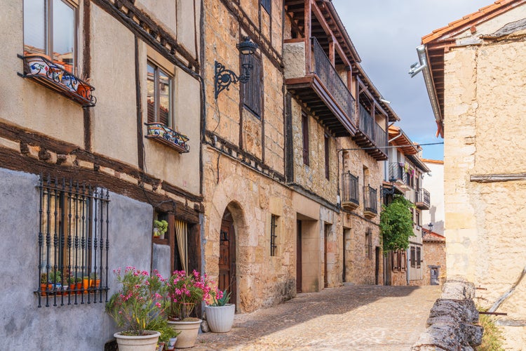 photo of view of Picturesque street showcasing traditional buildings decorated with flowers in a rural town. Frías, Burgos Province, Spain