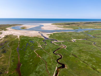 photo of aerial view of Dutch the Nationaal Park Duinen van Texel with curving rivers in grass land towards the North Sea on the Island of Texel, The Netherlands.