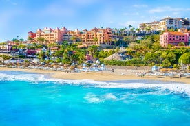 photo of aerial shot of Costa Adeje area, South Tenerife, Spain. Captured at golden hour, warm and vivid sunset colors. Luxury hotels, villas and restaurants behind the beach.