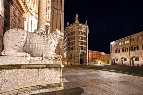 photo of view of Scenic night view of empty dome place, Parma Cathedral lion statue and baptistery during corona virus pandemic lockdown, Emilia Romagna, Italy.