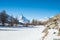 photo of winter forest with pine trees, snowy Matterhorn, frozen lake Grindjisee, mountains and blue sky with white clouds, Switzerland.