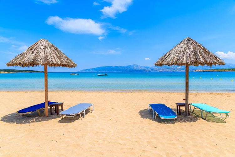 Photo of umbrellas with sunbeds on beautiful sandy Santa Maria beach with turquoise sea water, Parikia , Paros island, Greece