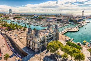 Photo of aerial view of Bilbao, Spain city downtown with a Nevion River, Zubizuri Bridge and promenade. Mountain at the background, with clear blue sky.