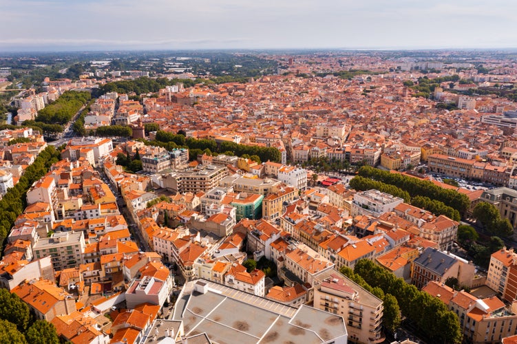 Photo of aerial view of Perpignan, France. Red rooftops of residential buildings visible from above.