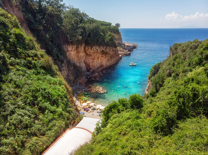 People swimming in crystal clear blue waters on a hidden beach. Bird View of a beautiful golf called Regina Giovanna in Sorrento, Italy