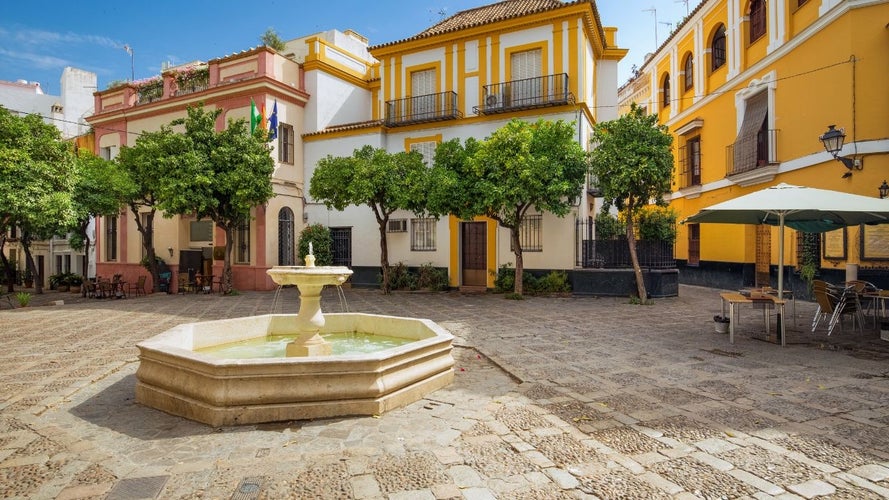 Charming plaza in Seville with a central fountain, surrounded by colorful buildings and lush orange trees..jpg