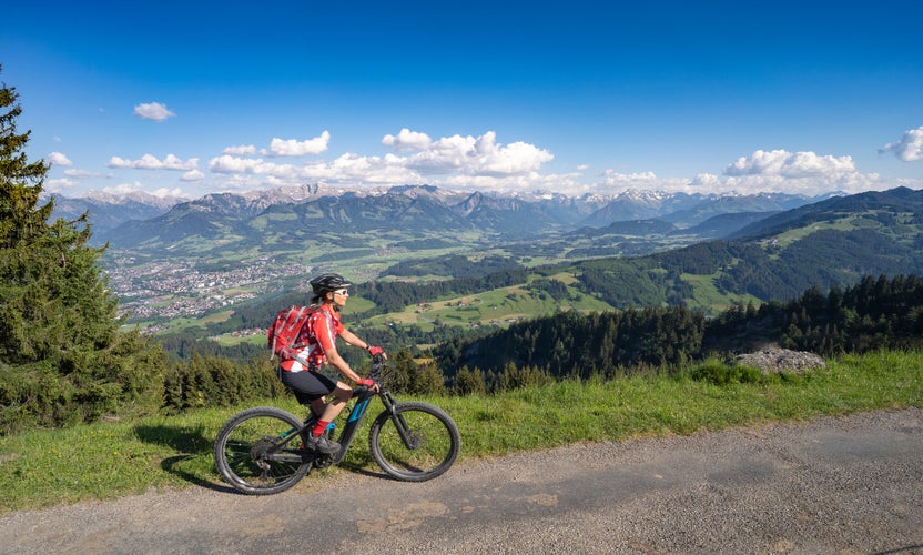 pretty senior woman riding her electric mountain bike on the mountains above the Iller valley between Sonthofen and Oberstdorf, Allgau Alps, Bavaria Germany