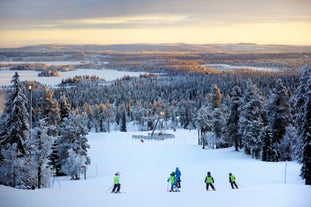 Photo of stunning sunset view over wooden huts and snow covered trees in Kuusamo, Finnish Lapland.