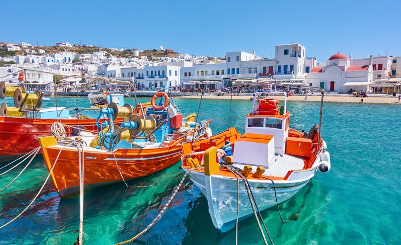 Photo of harbour with wooden fishing boats in Chora town on sunny summer day, Mykonos island, Greece.