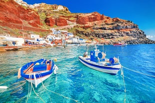 Photo of aerial view of black Perissa beach with beautiful turquoise water, sea waves and straw umbrellas, Greece.